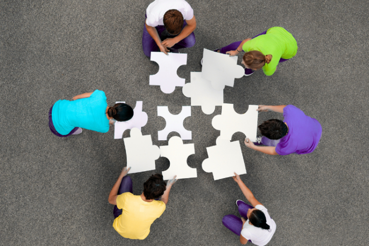 people with large puzzle tiles on grey background